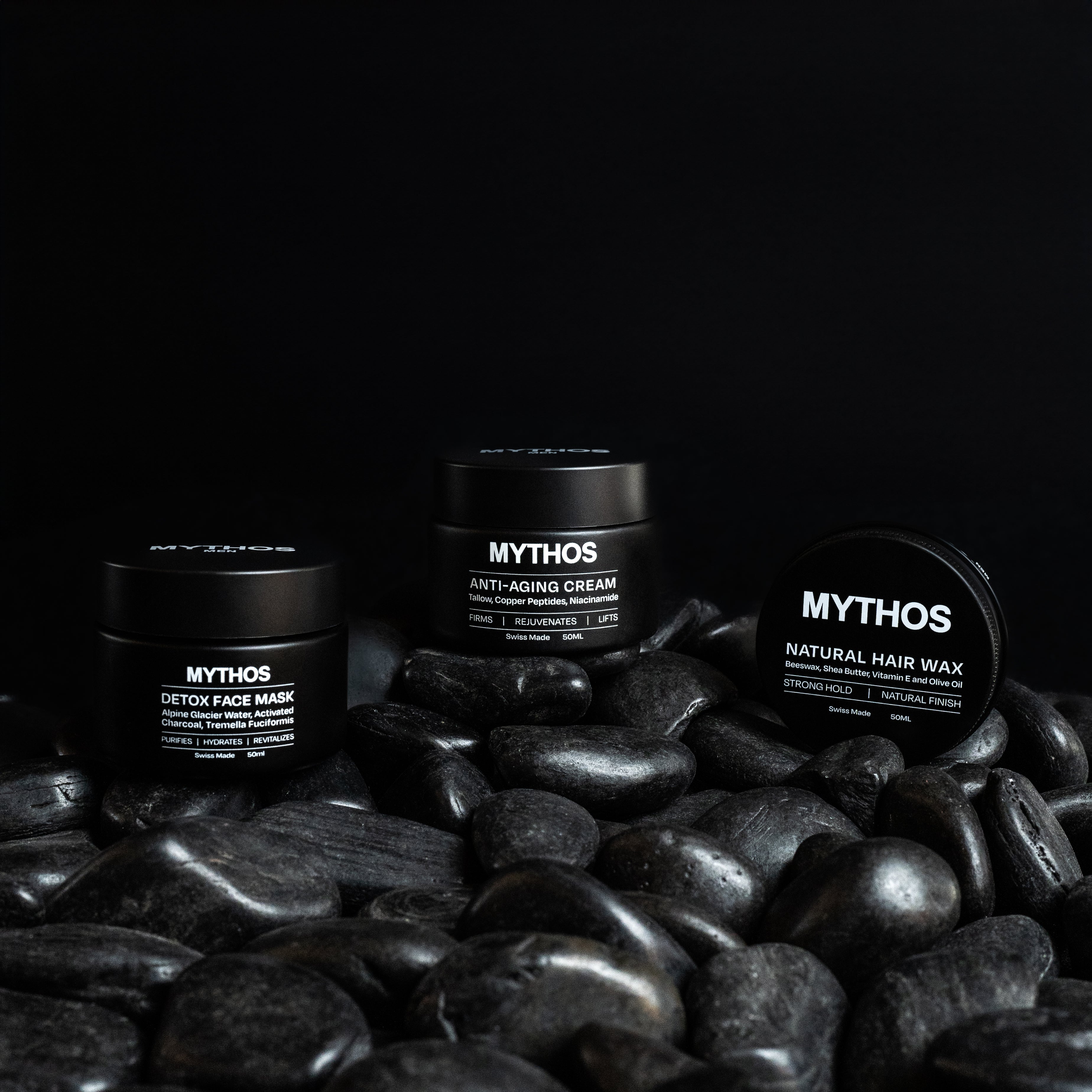 Mythos Men products shot in moody lighting on black stones and background